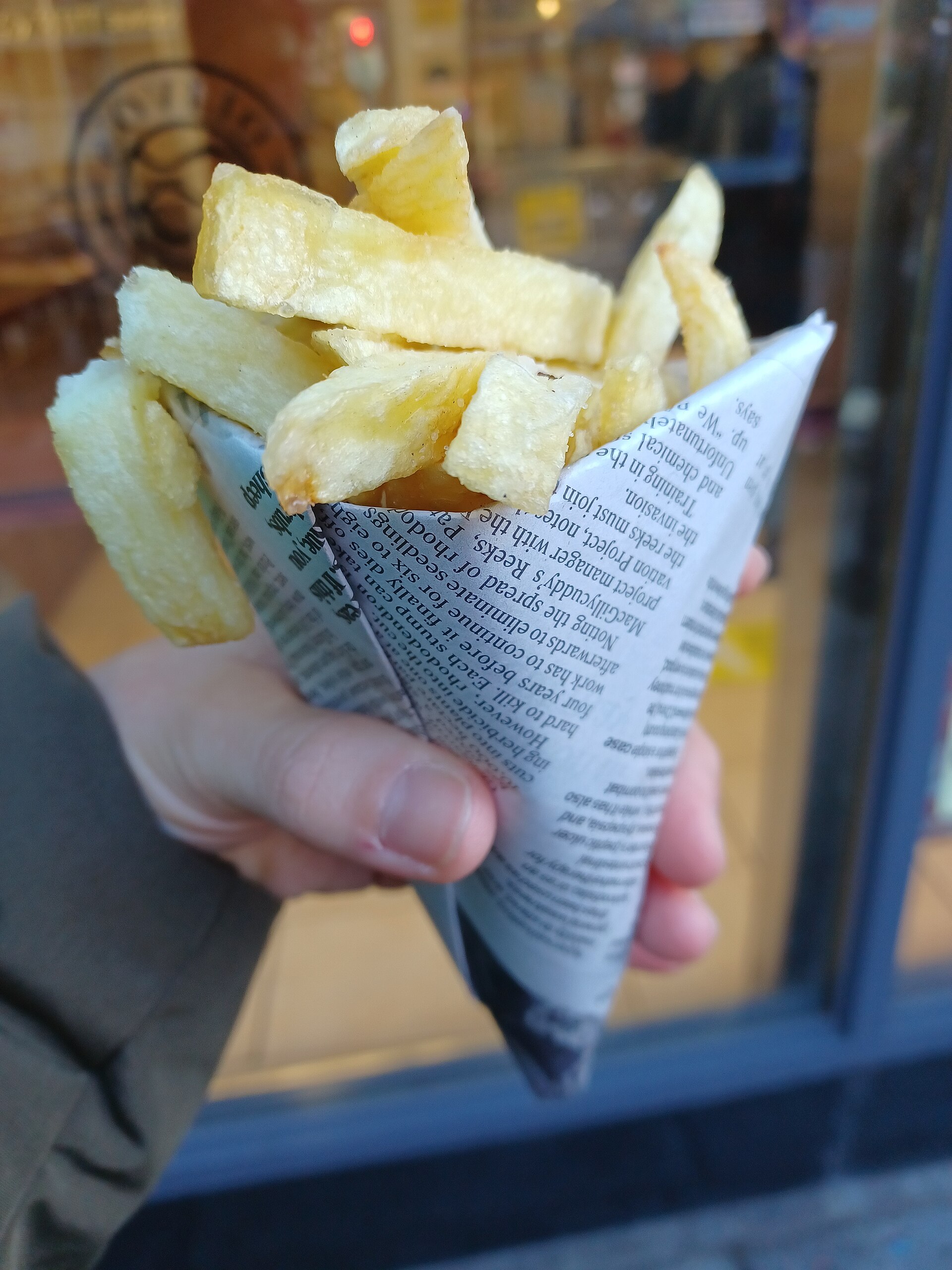 A hand holding chips in a newspaper cone (stand-in photograph)